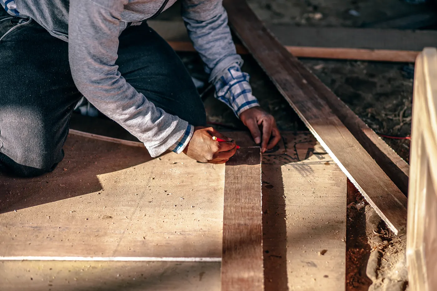 A contractor marking wood floorboards during an installation