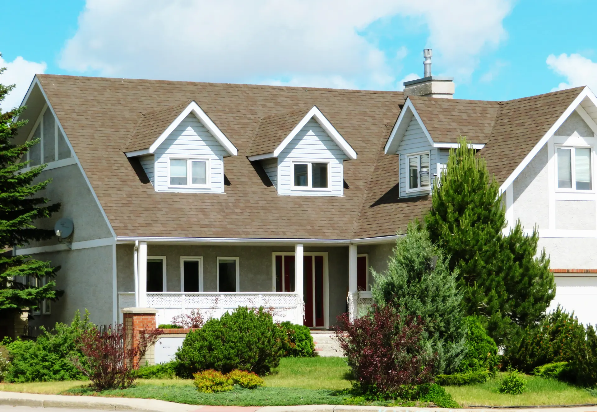 A two-story Long Island colonial home with a shingled roof and dormers